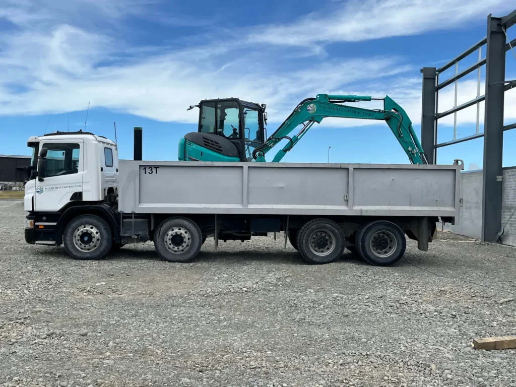 Flat-deck truck with an excavator loaded up on site